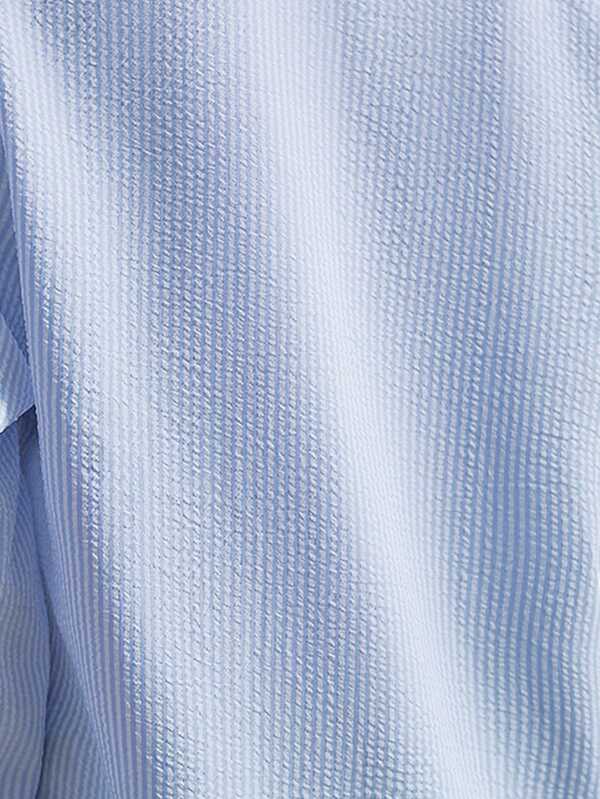 Chemise en seersucker bleu clair, texture gaufrée, tissu léger et respirant, idéal pour l'été, mode homme élégante et décontractée.