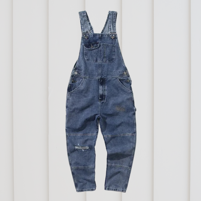 Salopette en jean bleu pour enfant suspendue sur fond blanc. Mode enfant, vêtement décontracté, tendance denim, style pratique et confortable.