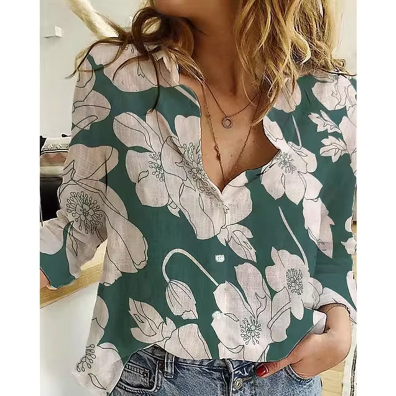 Chemisier femme à manches longues, motif floral vert et blanc, col en V, style décontracté, porté avec un jean bleu. Mode féminine tendance.