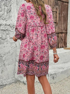 Robe rose à motifs floraux, manches longues, femme de dos, mur en pierre, porte en bois, style bohème, mode féminine, tendance printemps-été.