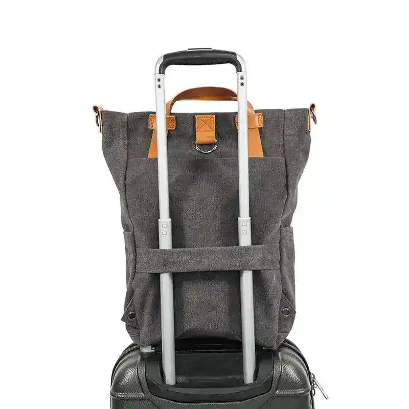 Sac à dos en toile grise fixé sur une valise à roulettes noire, idéal pour le voyage. Design pratique avec poignées en cuir marron.