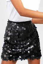Jupe noire à sequins brillants portée avec un t-shirt blanc, mode tendance, style chic et élégant, tenue de soirée glamour.