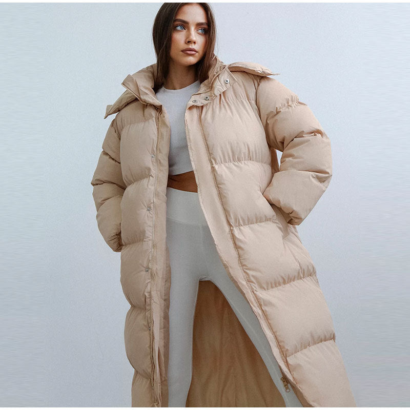 Femme portant un long manteau doudoune beige, tenue d'hiver élégante, mode féminine moderne, style décontracté, confort et chaleur.