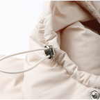 Détail d'une veste beige avec cordon de serrage et œillet métallique, mode hiver, vêtement chaud, style décontracté, tissu matelassé.