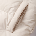 Doudoune beige avec poche latérale, tissu matelassé, style hiver, mode tendance, vêtement chaud, détail couture, textile isolant.