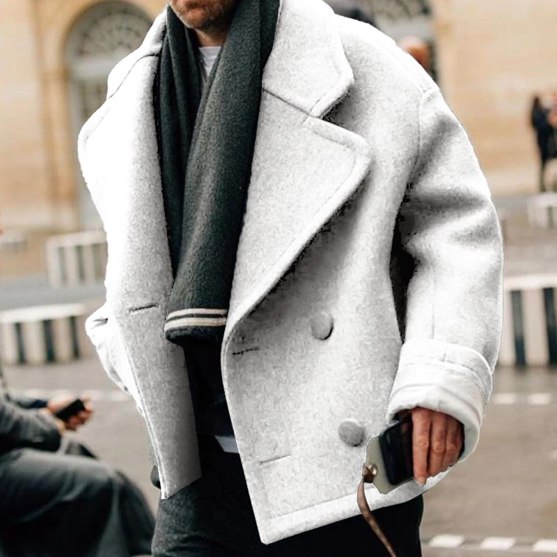 Homme portant un manteau blanc épais et une écharpe noire, tenant un smartphone. Mode hiver, style urbain, tendance masculine.