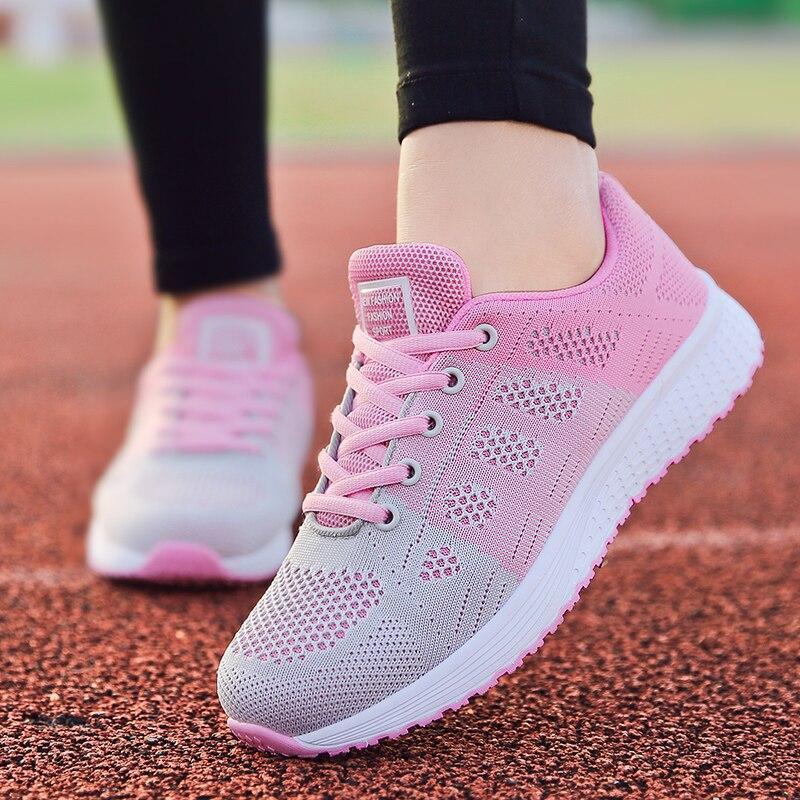 Baskets de course rose et gris sur piste d'athlétisme, chaussures de sport légères pour femme, semelle blanche, design respirant.