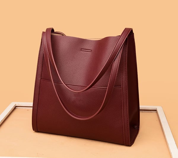 Sac à main en cuir marron foncé sur fond beige, design élégant et moderne, idéal pour la mode féminine. Accessoire tendance et chic.