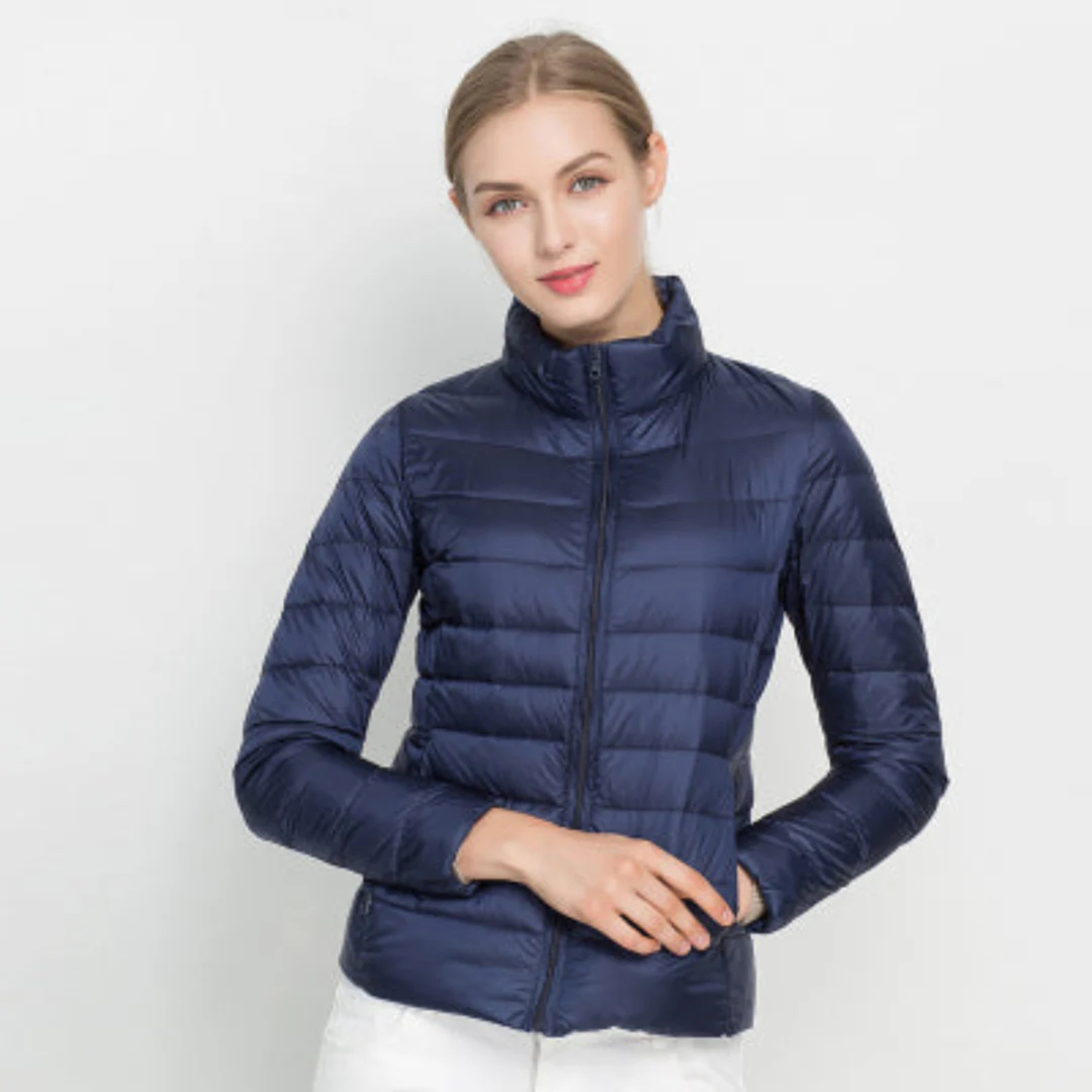 Femme portant une doudoune bleu marine, manches longues, fermeture éclair, sur fond blanc. Mode hiver, veste chaude, style décontracté.