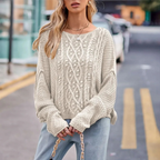 Femme portant un pull en tricot torsadé beige, posant dans une rue urbaine. Mode automne, style décontracté, tendance vêtements féminins.