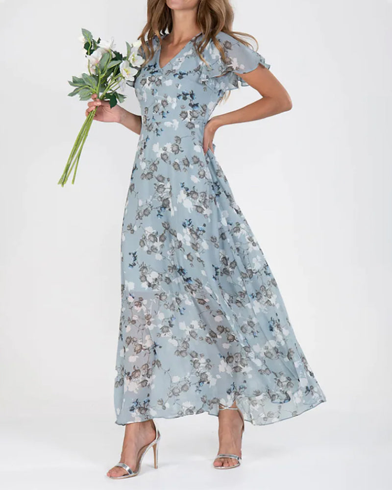 Robe longue fleurie bleue, manches courtes, portée par une femme tenant un bouquet de fleurs. Mode élégante, style estival, tenue chic.