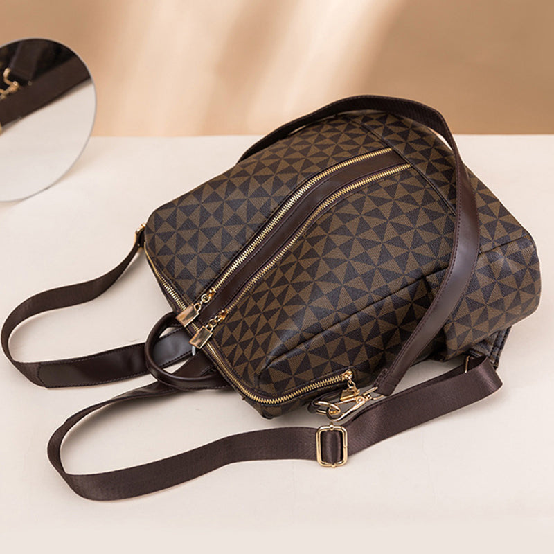 Sac à dos en cuir marron avec motif géométrique, fermetures éclair dorées et bretelles ajustables, posé sur une surface beige.