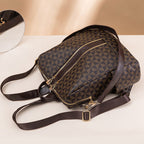 Sac à dos en cuir marron avec motif géométrique, fermetures éclair dorées et bretelles ajustables, posé sur une surface beige.