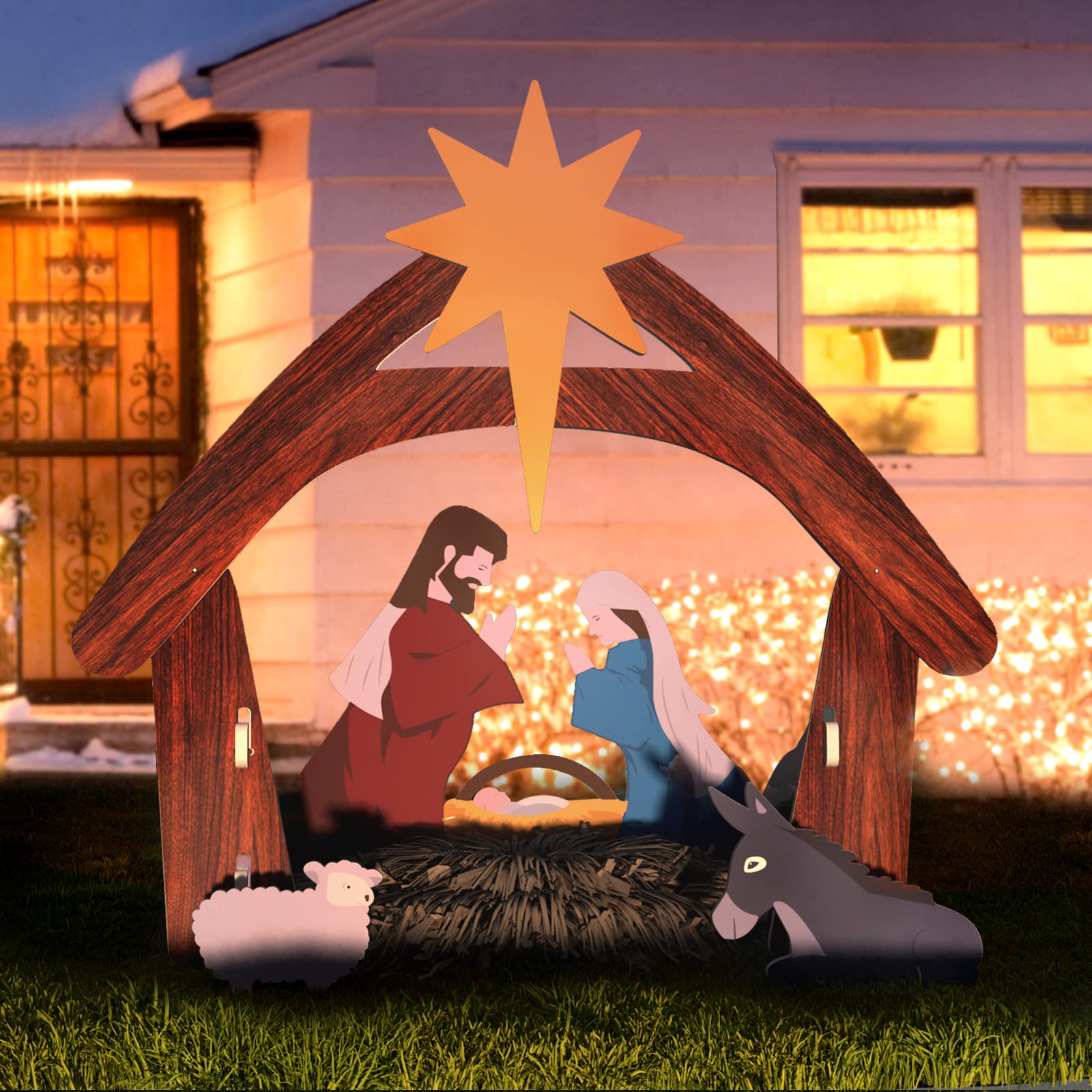 Crèche de Noël illuminée devant une maison, avec Jésus, Marie, Joseph, un âne et un mouton, sous une étoile dorée. Décoration festive extérieure.