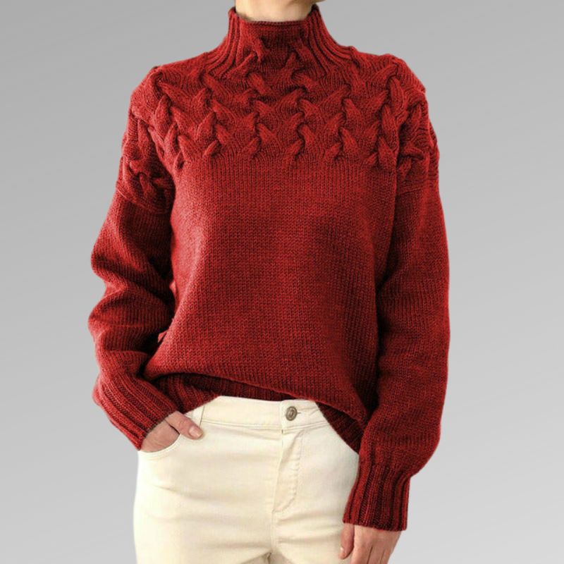 Pull rouge en laine torsadée pour femme, col montant, manches longues, porté avec un pantalon beige. Mode automne-hiver, style élégant et confortable.