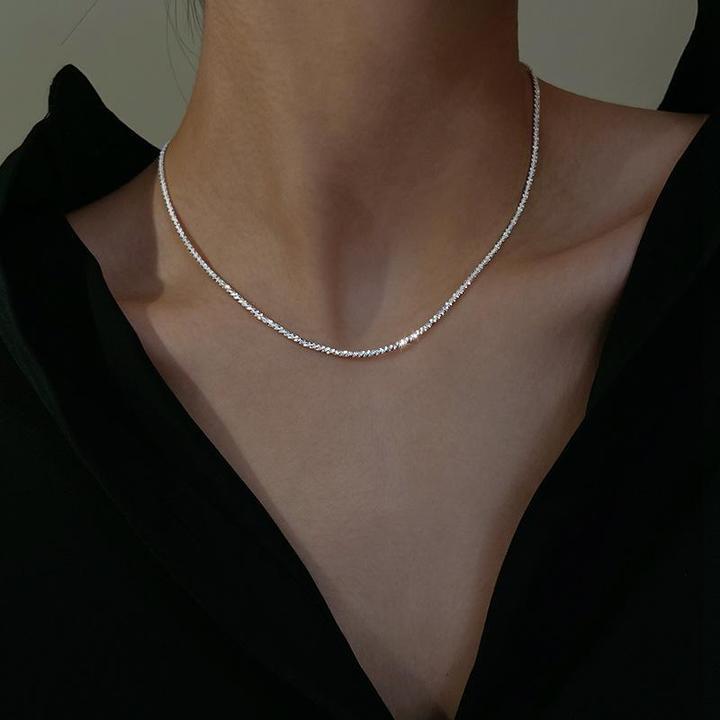 Collier en argent minimaliste sur un cou féminin, porté avec une chemise noire. Bijoux élégants, mode féminine, accessoire tendance.
