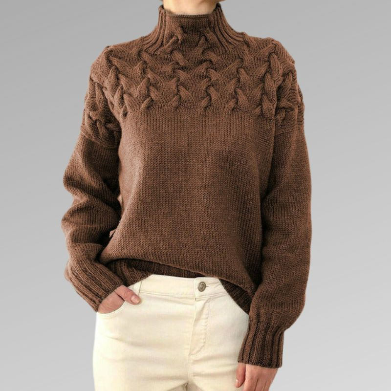 Pull en laine marron avec motif torsadé, col montant, manches longues, porté avec un pantalon beige. Mode automne-hiver, style décontracté.