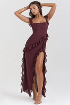 Robe longue bordeaux à volants, élégante et asymétrique, portée par une femme posant. Mode féminine, tenue de soirée chic.