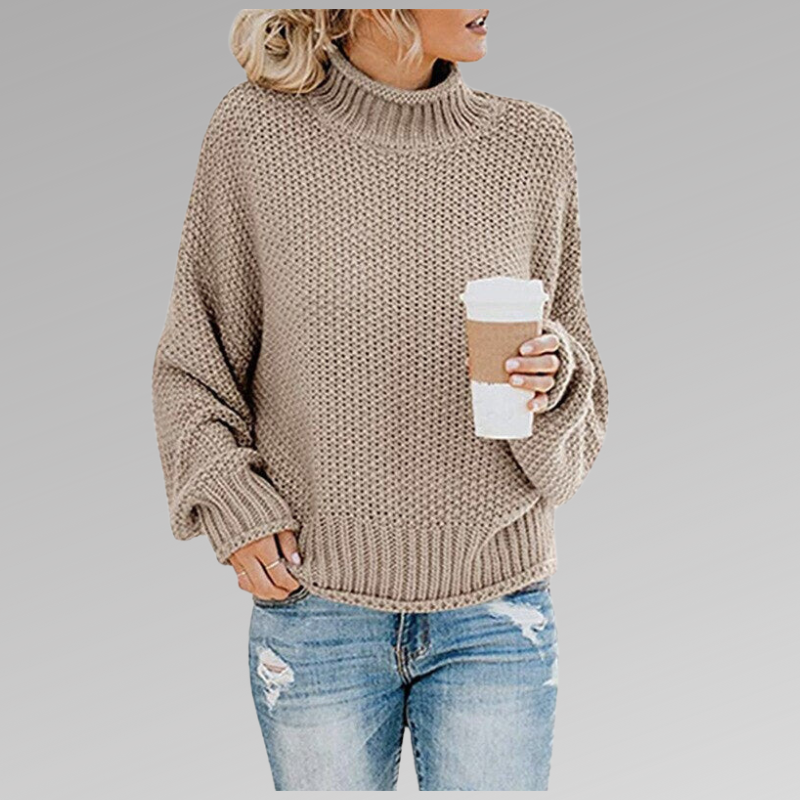 Femme en pull en maille beige, tenant un gobelet de café, portant un jean déchiré. Mode automne, style décontracté, tendance féminine.