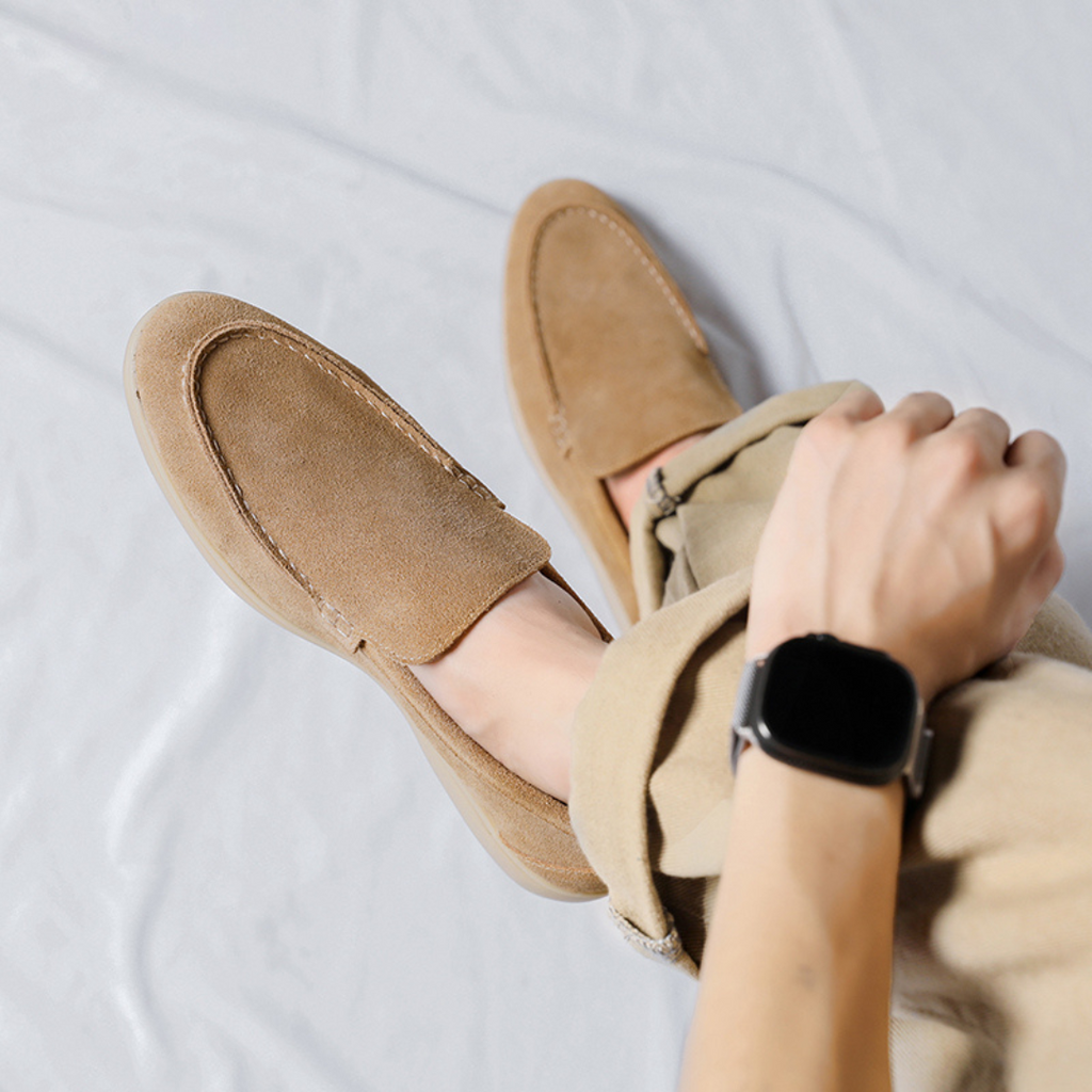 Chaussures mocassins en daim beige portées avec un pantalon beige, vue de dessus. Style décontracté, montre connectée au poignet.