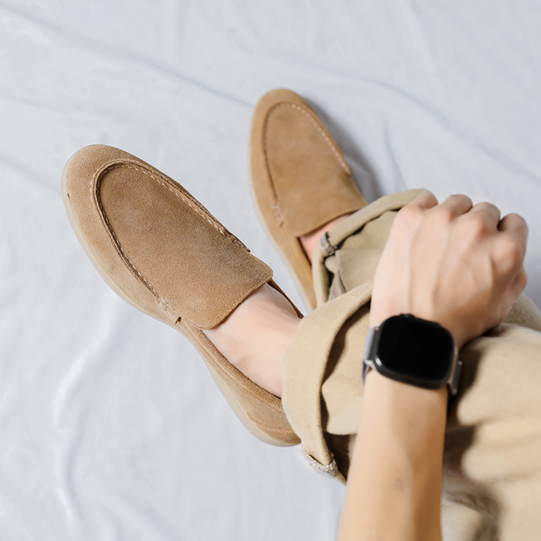 Chaussures mocassins en daim beige portées avec un pantalon beige, vue de dessus. Style décontracté, montre connectée au poignet.