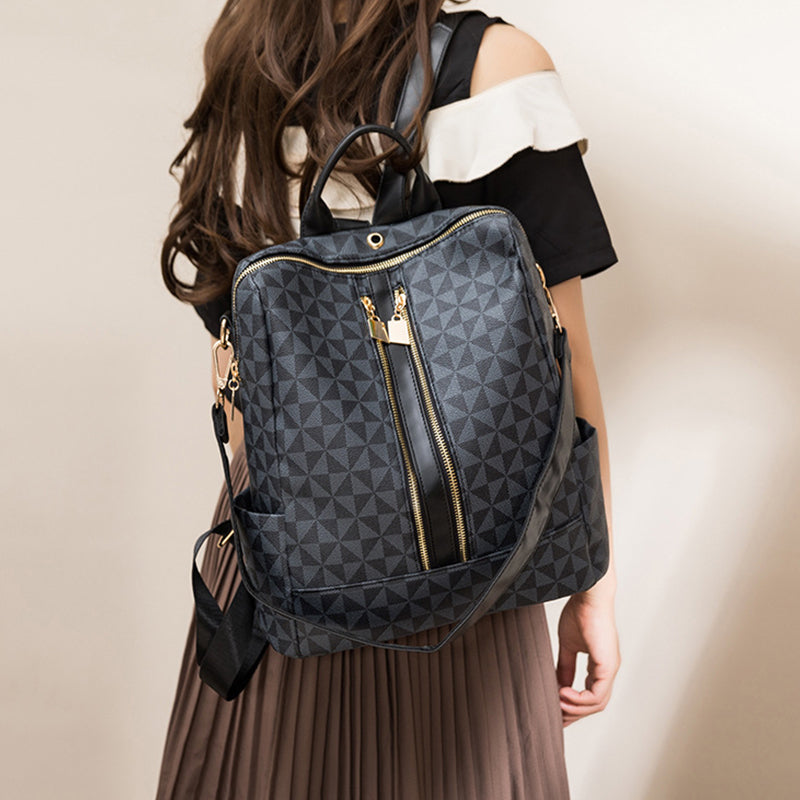 Sac à dos noir à motifs géométriques porté par une femme, avec fermeture éclair dorée et bretelles ajustables. Mode, accessoires, tendance.