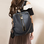 Sac à dos noir à motifs géométriques porté par une femme, avec fermeture éclair dorée et bretelles ajustables. Mode, accessoires, tendance.