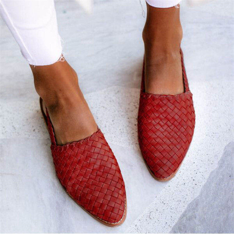 Chaussures rouges tressées en cuir pour femme, style mocassin, portées avec un pantalon blanc. Mode élégante et confortable.