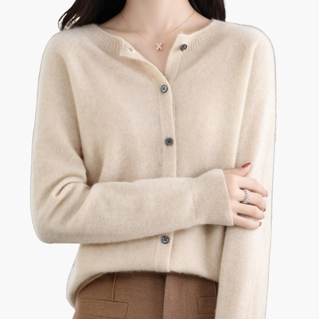 Femme portant un cardigan beige en cachemire avec boutons, collier délicat et pantalon marron. Mode élégante, tenue automne-hiver, style chic.