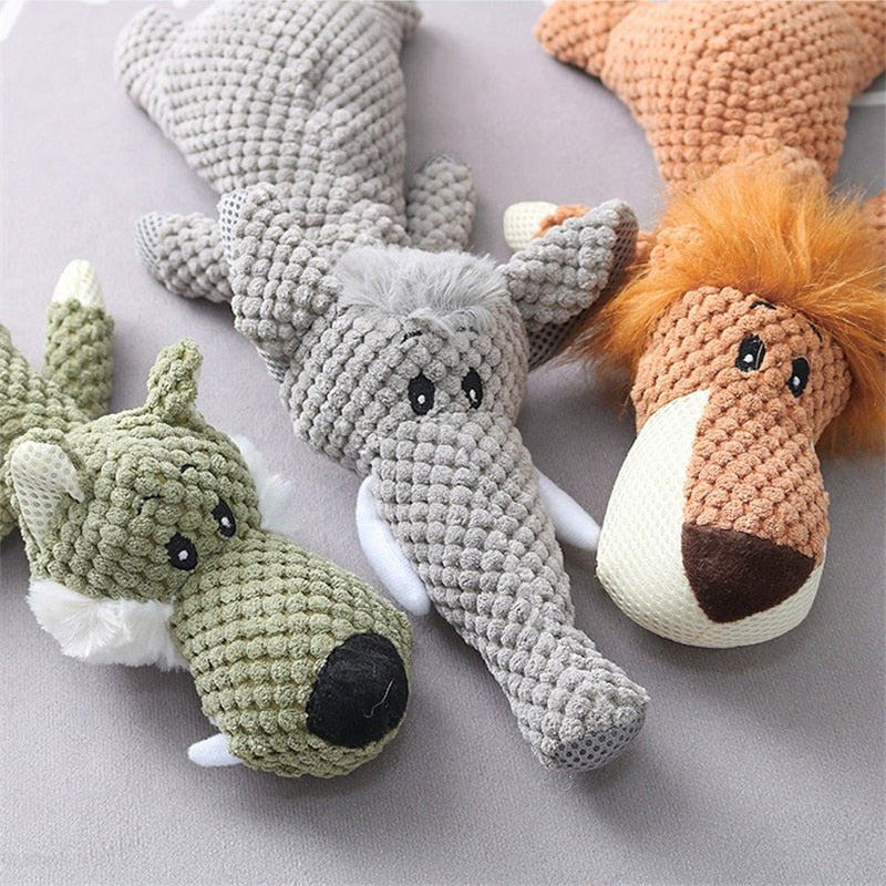 Trois peluches animales en tricot: un crocodile gris, un loup vert et un lion orange, posées sur une surface grise. Jouets doux pour enfants.