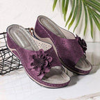 Sandales violettes élégantes avec fleurs décoratives, semelle confortable, posées sur fond blanc avec feuilles vertes. Chaussures d'été tendance.