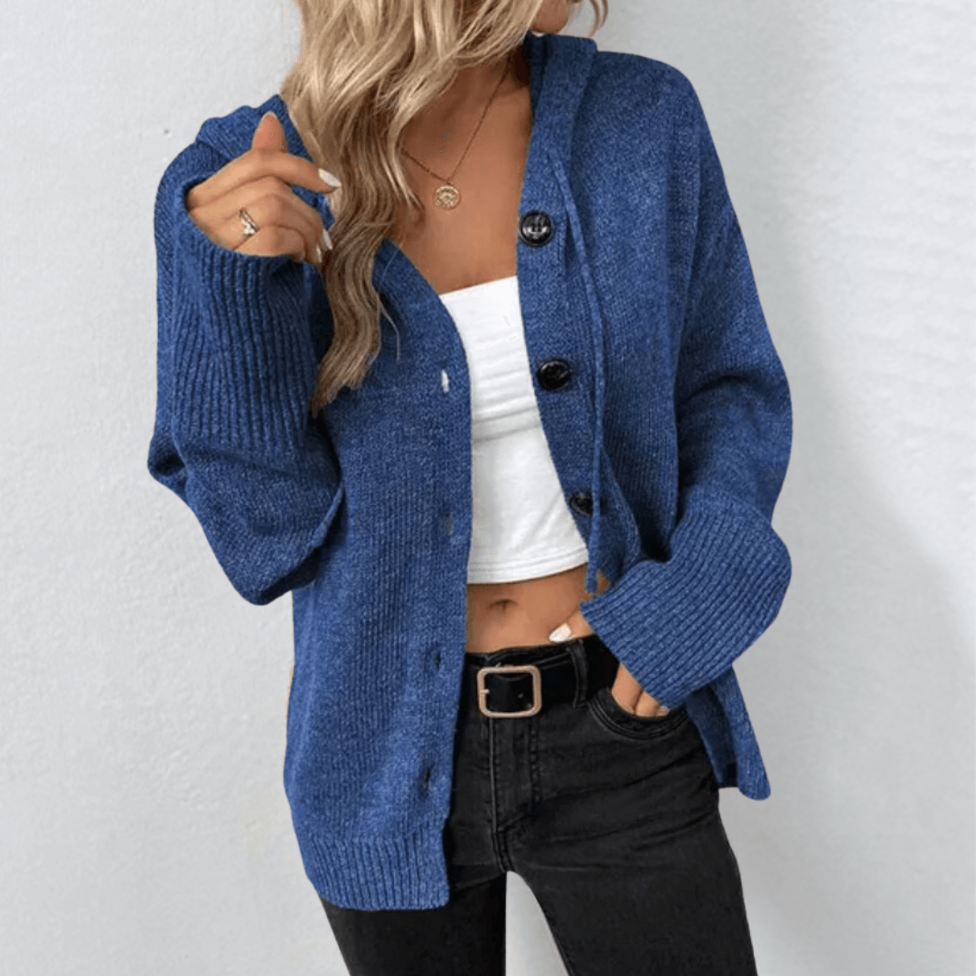 Femme portant un cardigan bleu en tricot avec boutons, débardeur blanc et jean noir. Mode automne, style décontracté, tendance féminine.