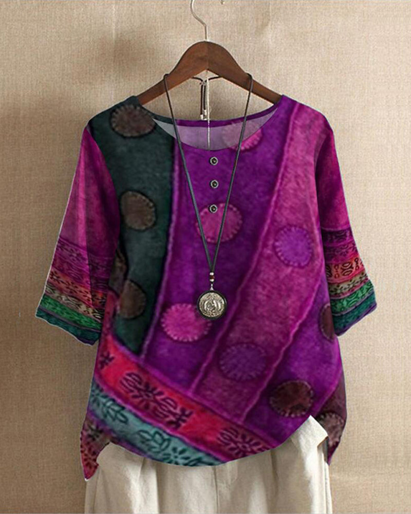 Blouse bohème chic violette à motifs ethniques, manches trois-quarts, col rond avec boutons, suspendue sur un cintre en bois.
