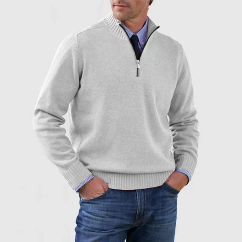 Homme portant un pull gris à col zippé, chemise bleue et jean. Mode masculine élégante, tenue décontractée chic, style automne-hiver.
