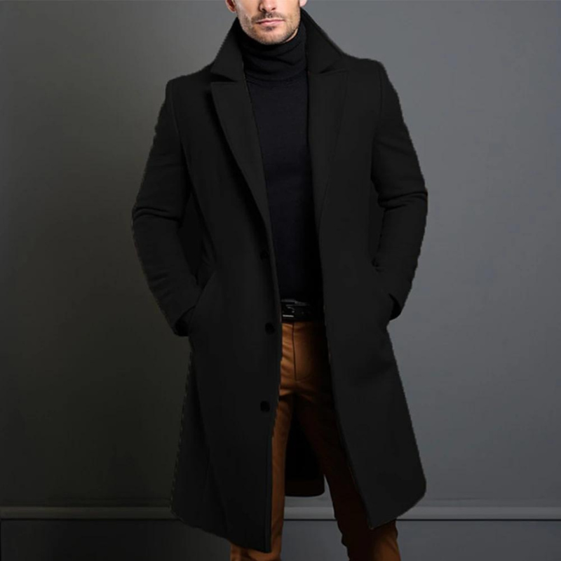 Homme portant un manteau noir élégant, col relevé, sur un pull noir et un pantalon marron. Mode masculine, style chic et moderne.