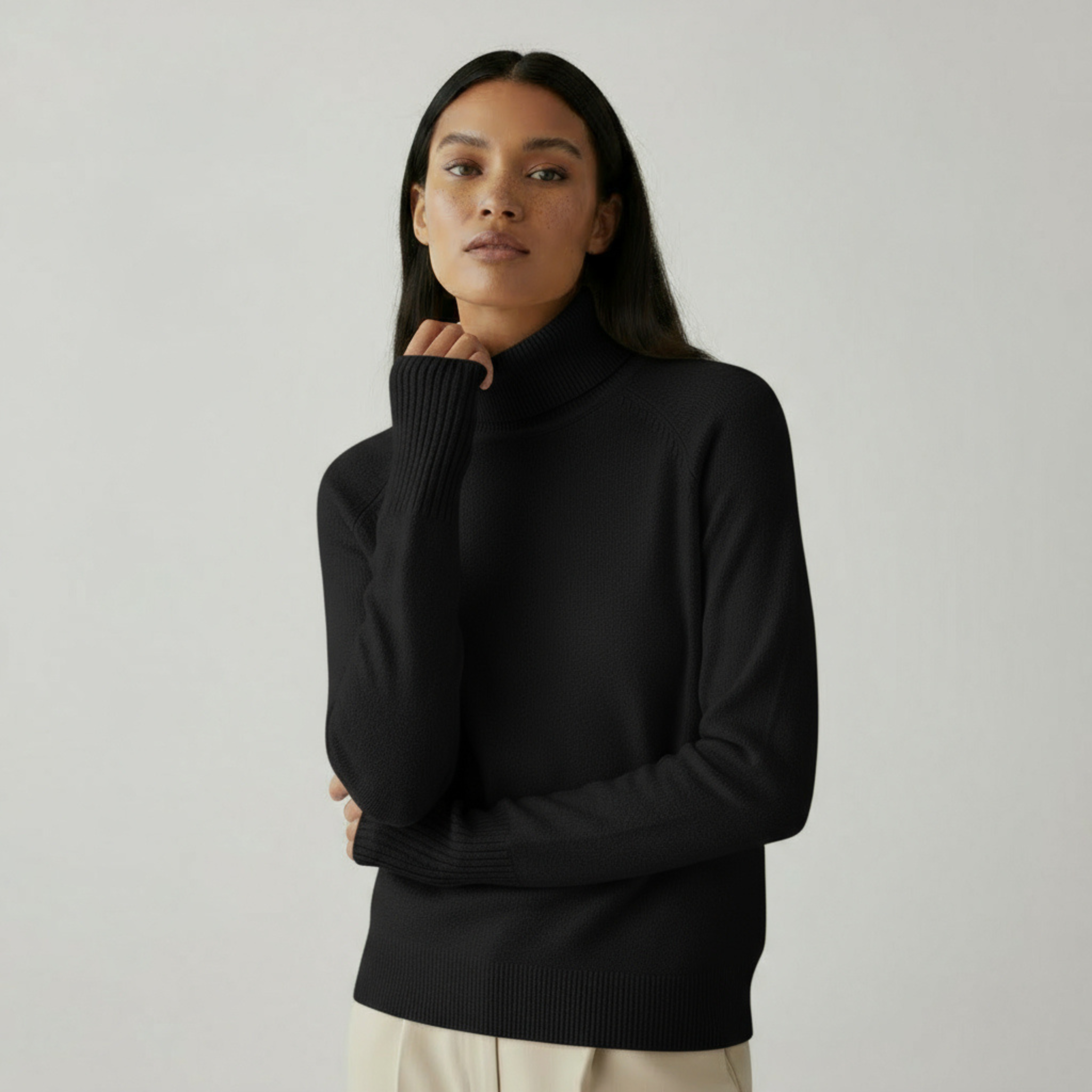 Femme portant un pull col roulé noir élégant, posant avec confiance. Mode automne-hiver, style minimaliste, tenue chic et moderne.