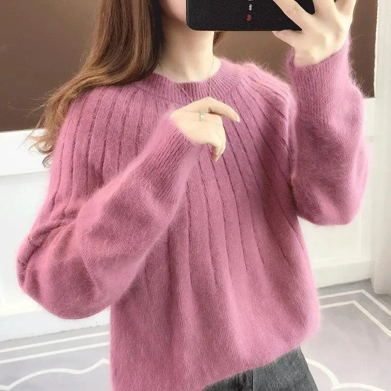 Femme portant un pull rose en laine, manches longues, col rond, prenant un selfie. Mode automne-hiver, vêtement chaud et confortable.