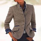 Veste en laine grise élégante pour femme, boutons argentés, poches à rabat, col montant, manches longues, style chic et moderne.