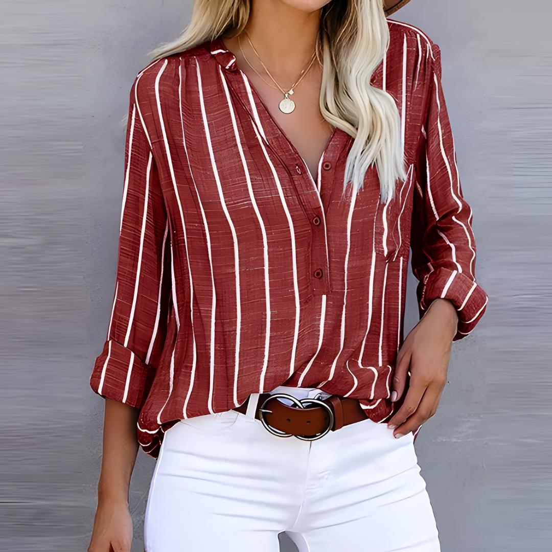 Chemise à rayures rouges et blanches pour femme, manches longues, col en V, portée avec un pantalon blanc et une ceinture marron. Mode décontractée élégante.