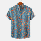 Chemise à manches courtes en lin bleu avec motif floral coloré, col mao, idéale pour l'été. Mode homme, style décontracté et tendance.