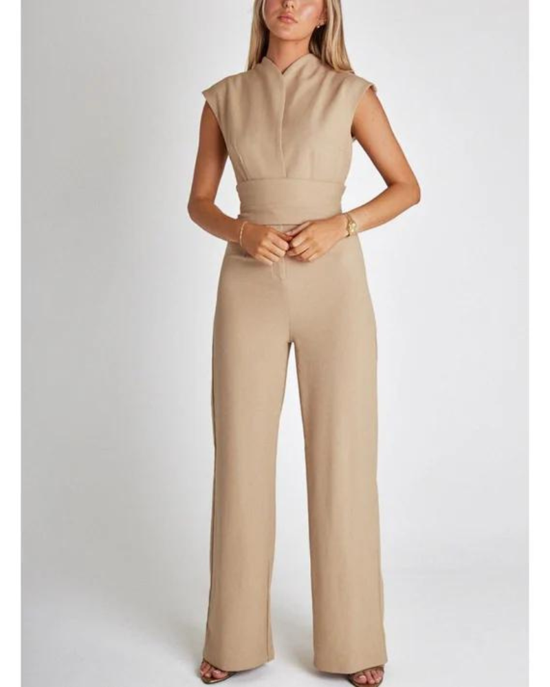Combinaison beige élégante pour femme, sans manches, avec ceinture intégrée, portée par un mannequin sur fond blanc. Mode féminine chic et moderne.