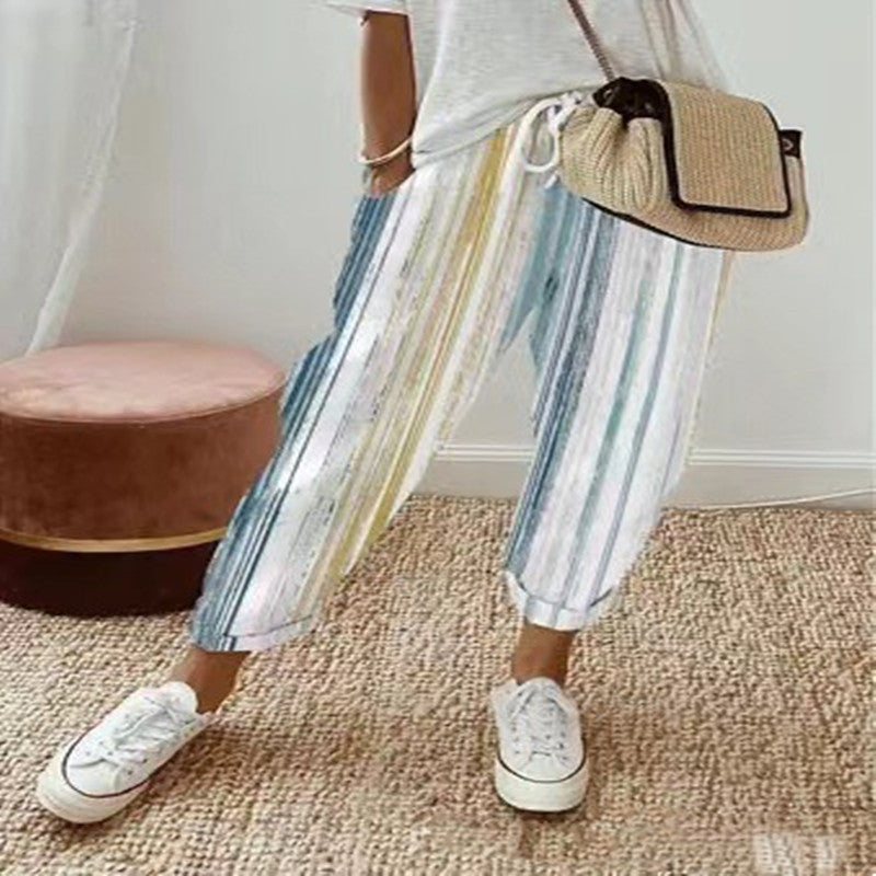 Pantalon rayé multicolore femme, style décontracté, avec t-shirt blanc et sac en osier. Mode estivale, tendance, confortable.