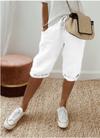 Femme portant un short blanc décontracté, t-shirt gris, baskets blanches et sac à main en paille. Mode estivale chic et confortable.