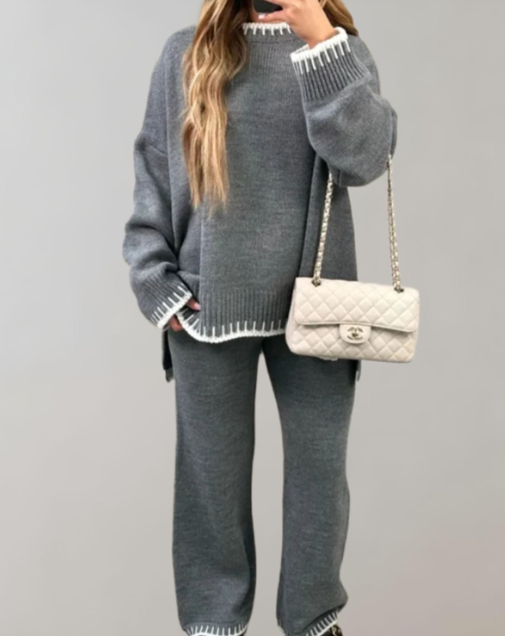 Femme en ensemble tricot gris avec sac à main Chanel blanc. Mode automne-hiver, style décontracté chic, tendance vêtements confortables.