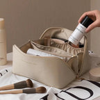Trousse de maquillage beige ouverte avec produits cosmétiques, pinceaux et flacon de spray. Accessoire beauté élégant pour organisation maquillage.