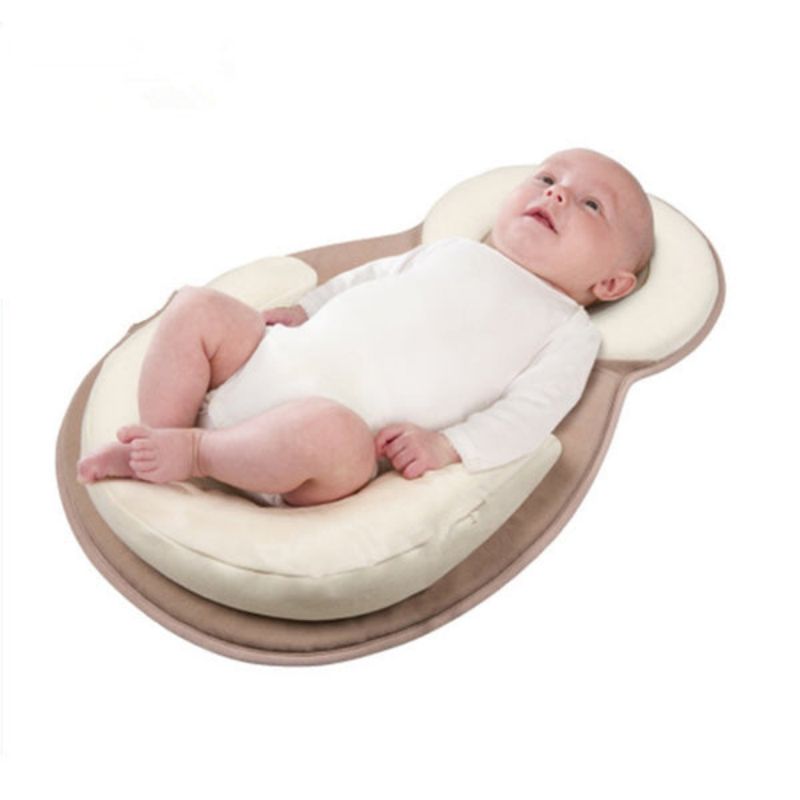 Bébé allongé sur un coussin ergonomique beige, vêtu d'un body blanc. Confort et sécurité pour nouveau-né, accessoire essentiel pour nourrisson.