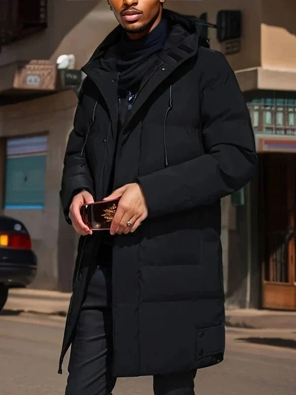 Homme portant un manteau noir élégant dans une rue urbaine, tenant un smartphone. Mode masculine, hiver, style moderne.