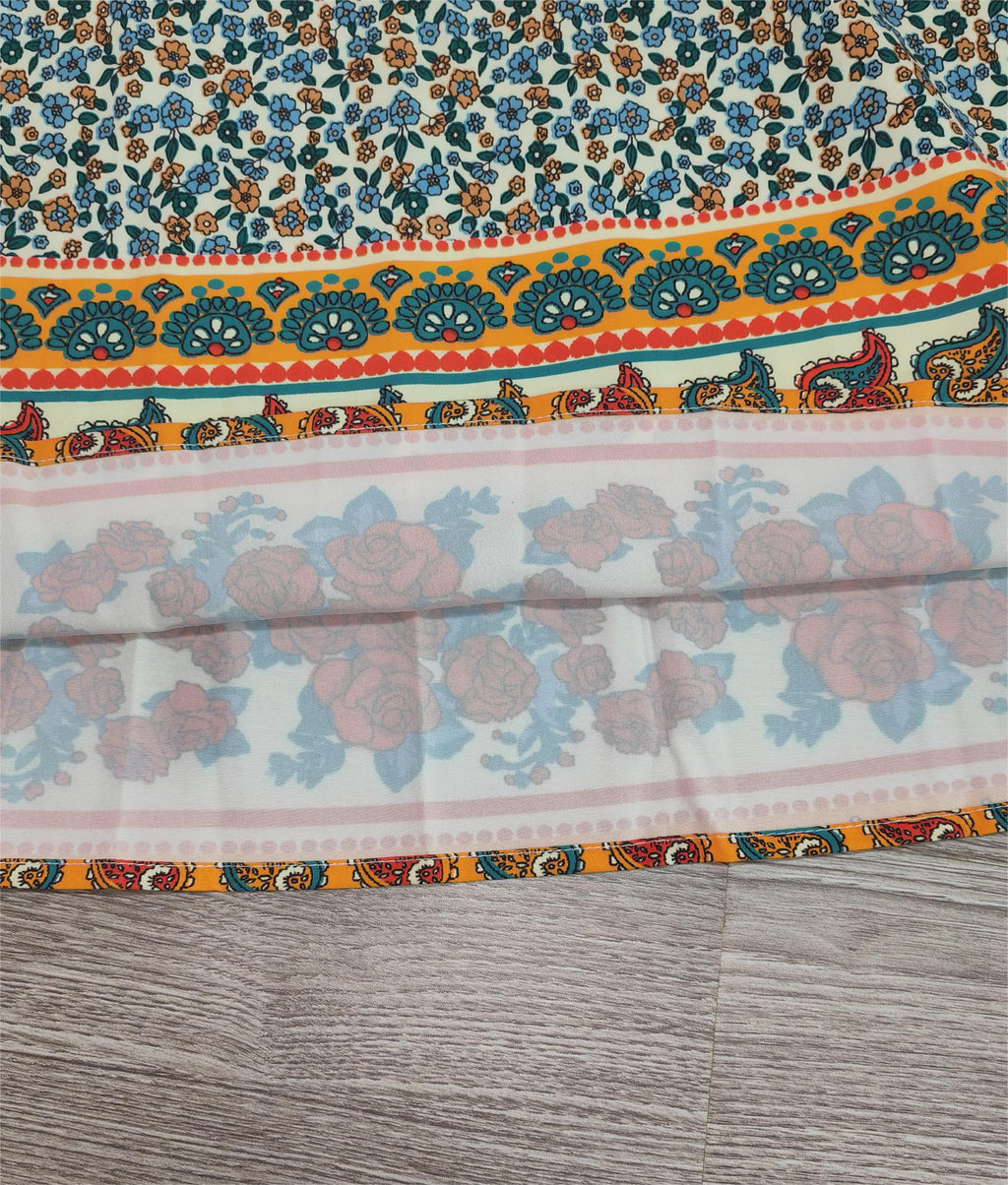 Écharpe en tissu imprimé floral avec motifs paisley colorés, bordure orange et bleue, posée sur un sol en bois. Accessoire mode tendance.