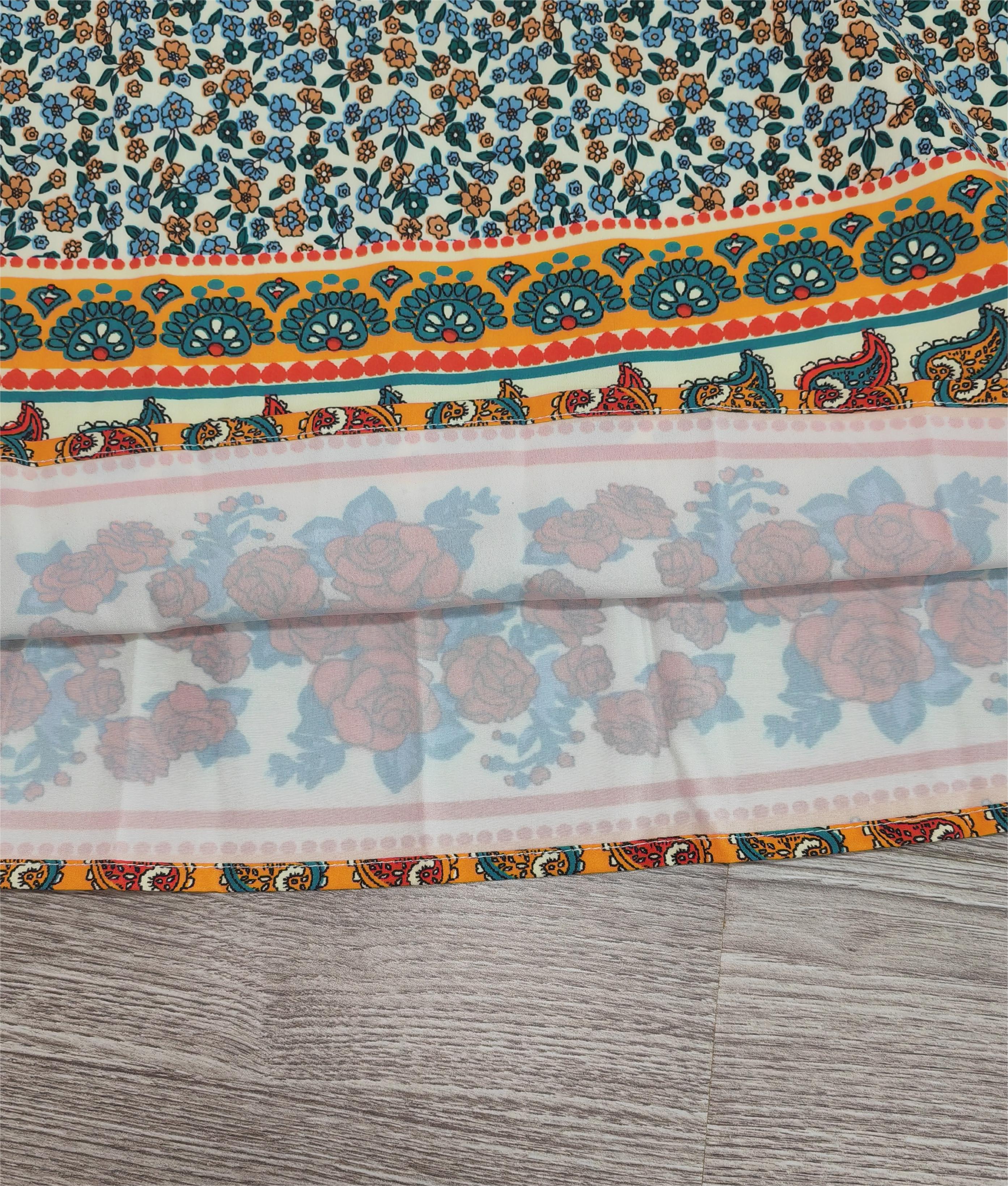 Écharpe en tissu imprimé floral avec motifs paisley colorés, bordure orange et bleue, posée sur un sol en bois. Accessoire mode tendance.