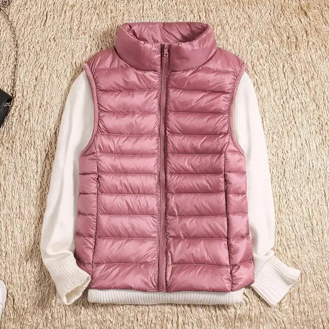 Gilet matelassé rose sans manches sur pull blanc, posé sur tapis beige. Mode automne-hiver, vêtements chauds, style décontracté et tendance.